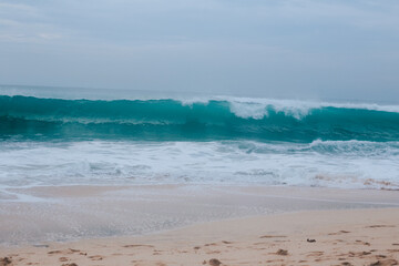 Fototapeta na wymiar A large turquoise wave near the shore. Wave for surfers in the form of a tube