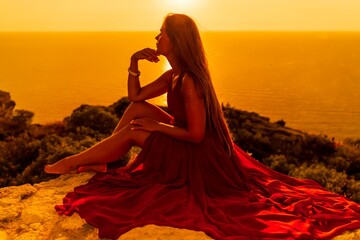 Woman sunset sea red dress, side view a happy beautiful sensual woman in a red long dress posing on...