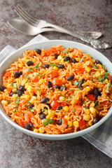 Mexican tomato rice with black beans, onions and corn close-up in a bowl on the table. Vertical
