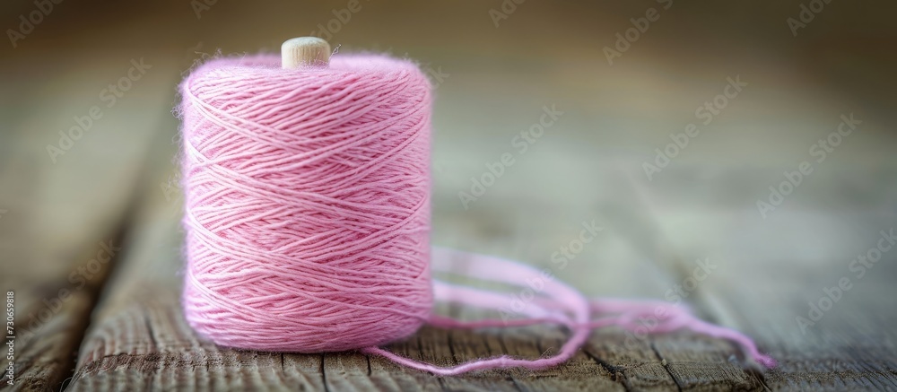 Poster softly focused pink thread on a wooden table with shallow depth of field.