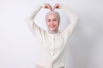 Young Muslim woman with braces making a love heart shape with hands on her head