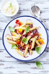 Penne pasta with yellow and red pepper, hard cheese and fresh basil. Bright background. Close up.	