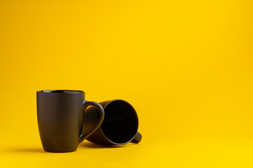 Two mugs on yellow studio background close up