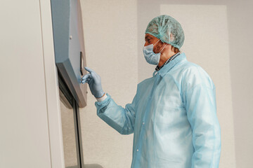 Male scientist in uniform and mask working in medical research laboratory use special equipment