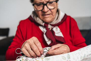 seamstress dressed in red, with glasses, working with scissors on a garment