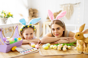 easter, mom and little daughter with bunny ears on their head are preparing for the holiday by having fun playing and spending time together, colorful eggs, lifestyle,