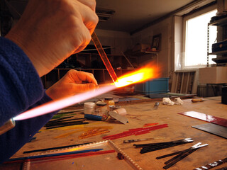 Close up of artist hands creating glass pendant with lampworking technique