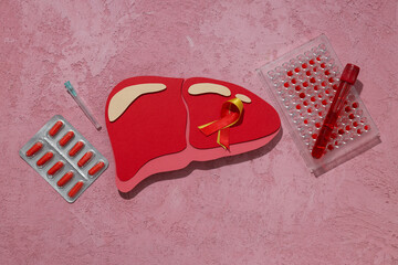Paper liver, pills and test tubes on pink background, top view