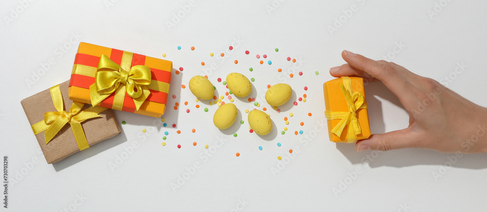 Wall mural Chocolate eggs with gifts on a light background