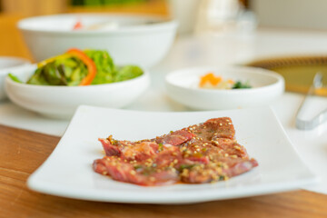 Japanese yakiniku (grilled meat) served alongside a bowl of refreshing cold noodles. The yakiniku features tender, perfectly grilled slices of meat with a caramelized glaze