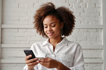 African American Girl wearing in white wear using smartphone pressing finger, reading social media internet, typing text or shopping online Mobile phone in two black hands 