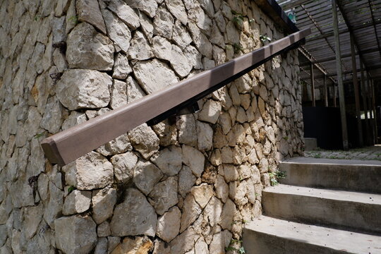 The stair handrails are made of wood and installed in the mountain stone wall. for the concept of illustrating housing exterior design