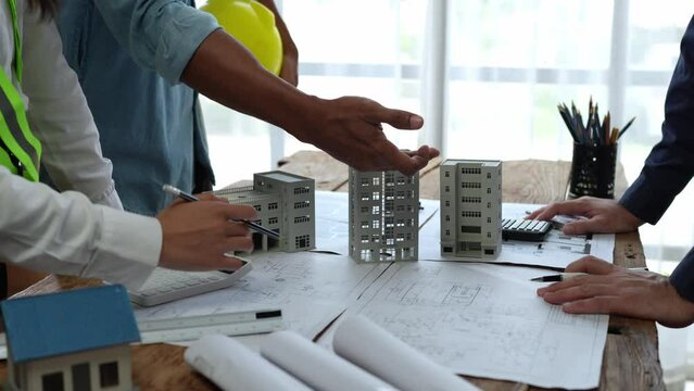 Team of engineers meeting holding worker helmets in city construction office Industrial Project Manager Foreman Engineer meeting to work as a team Professional team in Asian industry.