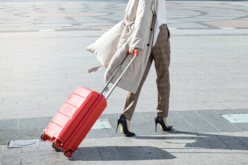 Young female traveler walking with a red suitcase at the modern transport stop outdoors, travel concept of vacation and holiday.