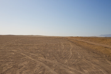 Desert road for buggy and ATV with tire tracks on the sand against the backdrop of the endless...