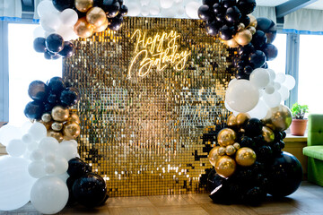 Photo zone with golden sparkles, balloons and the inscription Happy Birthday.