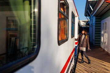 young girl with a backpack enters the train and smiles at the camera. A girl travels by train.