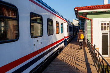 young girl with a backpack walks along the station platform.