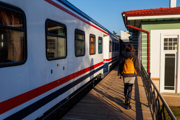 young girl with a backpack walks along the station platform.