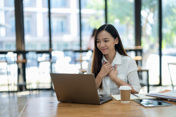 Content Asian businesswoman smiling and feeling grateful during a pleasant conversation over a...