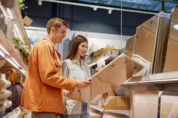 Happy loving couple choosing wall picture for home decoration at store