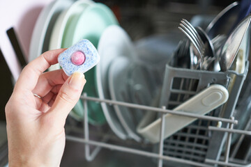 Woman's hand holding a dishwasher detergent in the dishwasher