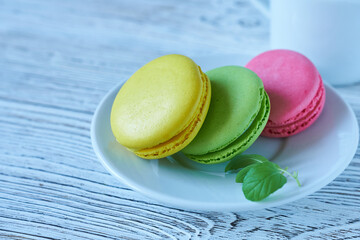 Colorful macaroons on a white plate on a wooden background