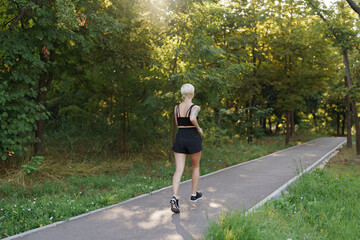 A solitary female runner jogs on a shaded forest path in the tranquility of morning light