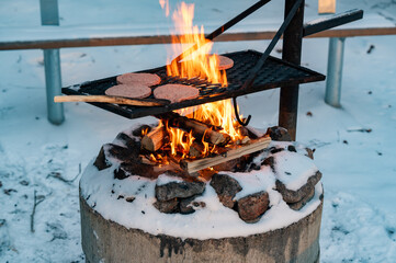 Hamburger on cooking grate over big flames