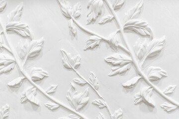 Gypsum plaster floral ornament. Decoration for the wall. White wall with floral ornament. Floral facade design
