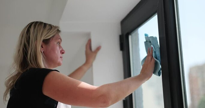 Concentrated woman cleans glass surface washing windows