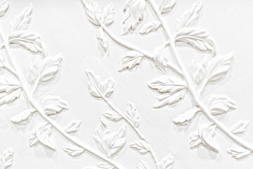 Gypsum plaster floral ornament. Decoration for the wall. White wall with floral ornament. Floral facade design