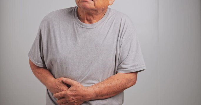 An elderly Asian man has tummy ache. Old man has stomach ache.