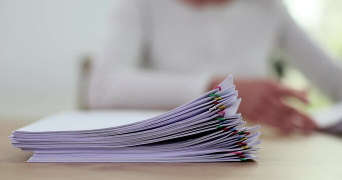 Woman puts papers on table in stacks with color paper clips