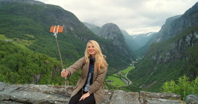 Mountains, nature or happy woman in outdoor selfie with confidence or smile on a holiday vacation. Vlog, influencer or person hiking in Norway for travel or taking a photograph or picture for memory