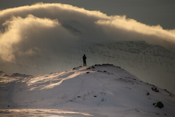 hiker in front of snowy mountains and clouds