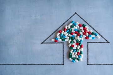 Upward-pointing arrow and a pile of colorful pills. High demand, rising costs of...