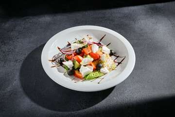 Greek salad with feta cheese and Kalamata olives drizzled with balsamic reduction
