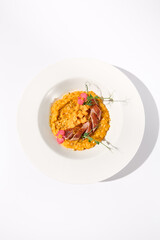 Top view of duck breast with pumpkin risotto on white, ideal for autumn menu promotions and food blogging