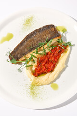 Pan-seared trout fillet with creamy potato puree and tomato salsa on a white plate, top view for gourmet seafood cuisine