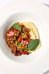 Braised beef with vegetables and mushrooms, topped with mashed potatoes on a white background, top view - perfect for comfort food menus