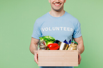 Cropped young man wears blue t-shirt white title volunteer give box with vegetarian vegan food...