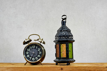 alarm clock with lantern on wooden table , ramadan concept 