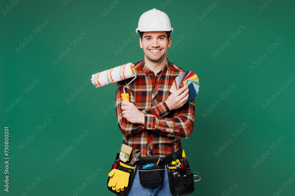 Wall mural young laborer man wearing red shirt hardhat hat hold color wallpaper palette paint brush isolated on