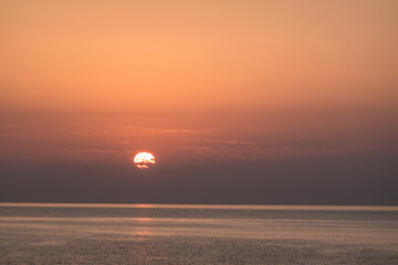 entwined sun with small clouds during sunrise at the red sea