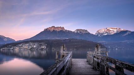 Paysage du lac d'Annecy en Haute-Savoie au coucher du soleil en hiver entouré de montagne dans les Alpes françaises - obrazy, fototapety, plakaty