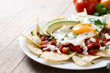Fototapeta na wymiar Traditional Mexican breakfast red chilaquiles with egg on wooden table. 