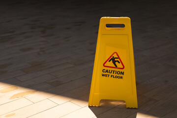 Wet floor caution sign on walkway. Warning yellow plastic caution wet floor sign on the ground with copy space.
