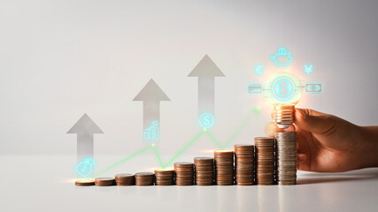 Hand holding glowing light bulb over coin stack with up arrow icons. Income management concepts