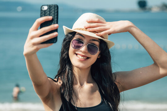 smiling tourist girl making a selfie or live video on the beach